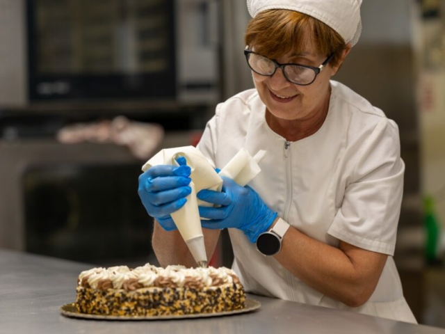 signora dello staff che decora una torta nel laboratorio